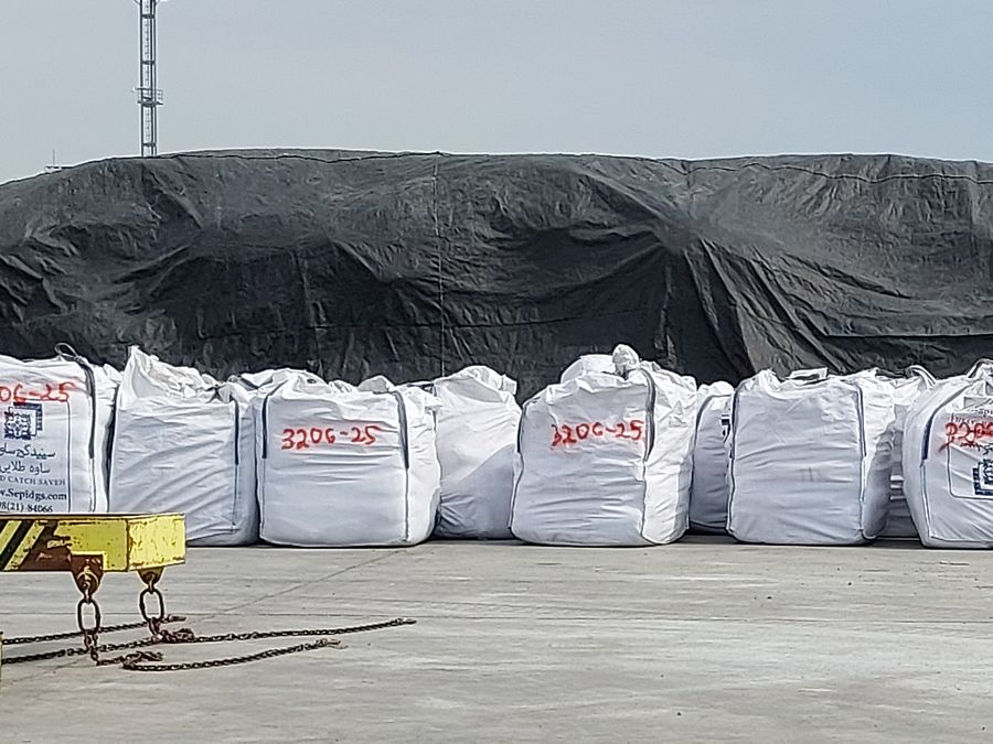 Big bags lined up on a port quay under cranes