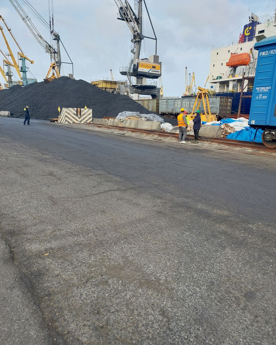Dry bulk stockpile on a port quay beside a vessel